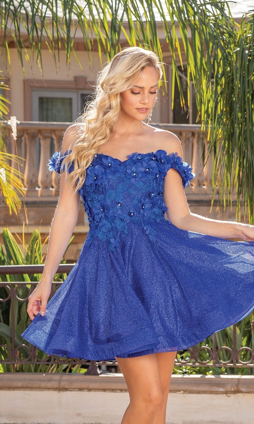 A woman stands outdoors near palm trees and a railing, wearing an affordable Corset-Back Babydoll Short Metallic Prom Dress featuring an off-the-shoulder blue design with floral embellishments.